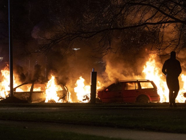 A protester stands next burning cars in Malmo on April 17, 2022. - Plans by a far-right gr