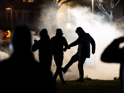 A protester kicks a tear gas canister at Rosengard in Malmo on April 17, 2022. - Plans by