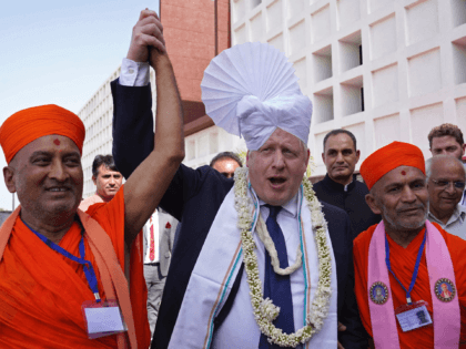 Britain's Prime Minister Boris Johnson (C) gets a traditional turban tied on his head upon his arrival at the Gujarat Biotechnology University in Gandhinagar on April 21, 2022. (Photo by Stefan Rousseau / POOL / AFP) (Photo by STEFAN ROUSSEAU/POOL/AFP via Getty Images)