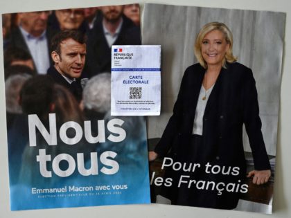 An electoral card is shown in front of posters of far-right Party (RN) presidential candidate Marine Le Pen (R), and incumbent President and candidate for his reelection Emmanuel Macron (L) in Montpellier, southern France, on April 21, 2022. - President Emmanuel Macron and far-right rival Marine Le Pen launched a …