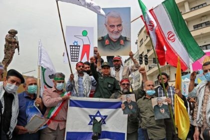 Iranians prepare to set an Israeli flag on fire next to a picture of late Iranian general Qasem Soleimnai during a rally marking al-Quds (Jerusalem) day in Tehran, on April 29, 2022. - An initiative started by the late Iranian revolutionary leader Ayatollah Ruhollah Khomeini, Quds Day is held annually …