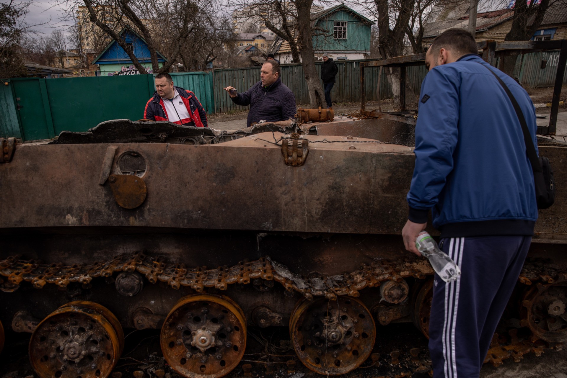BUCHA, UKRAINE - APRIL 06: People look at a destroyed Russian military vehicle on a street on April 06, 2022 in Bucha, Ukraine.  The Ukrainian government has accused Russian forces of: a 