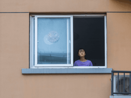 A girl looks from a window in a residential area on April 12, 2022 in Shanghai, China. Some 25 million people in Shanghai are in the second week of a strict lockdown, after a surge in Omicron cases. (Photo by Getty Images)