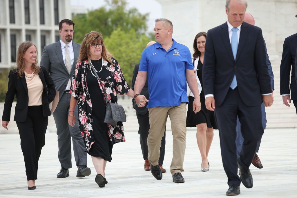 WASHINGTON, DC - APRIL 25: Former Bremerton High School assistant football coach Joe Kennedy holds hands with his wife Denise as he walks in front of the U.S. Supreme Court with members of his legal team after his case, Kennedy vs. Bremerton School District, was argued before the Supreme Court April 25, 2022 in Washington, DC. Kennedy was terminated from his job by Bremerton public school officials in 2015 after refusing to stop his on-field prayers after football games. (Photo by Win McNamee/Getty Images)