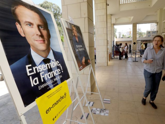 French citizens residing in Lebanon walk past election posters of independent centrist French presidential candidate Emmanuel Macron (L) and far-right Front National (FN - National Front) candidate Marine Le Pen, as they arrive to cast their votes at the French embassy in Beirut on May 7, 2017 during the second …