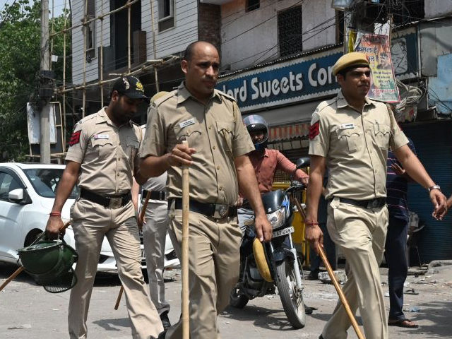 Police walk along a street in Jahangirpuri area in New Delhi on April 17, 2022, after clas