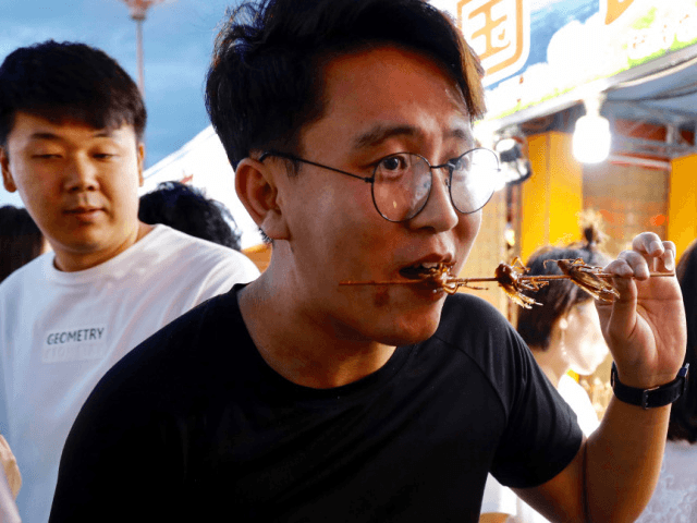 This picture taken on June 30, 2019 shows a man eating a stick of roasted insects at a food market in Shenyang in China's northeastern Liaoning province. (Photo by STR / AFP) / China OUT (Photo credit should read STR/AFP via Getty Images)