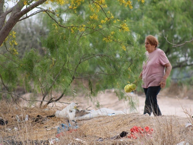 A migrant woman discards trash after illegally crossing the border near Eagle Pass, Texas, on the eve of Easter. (Randy Clark/Breitbart Texas)