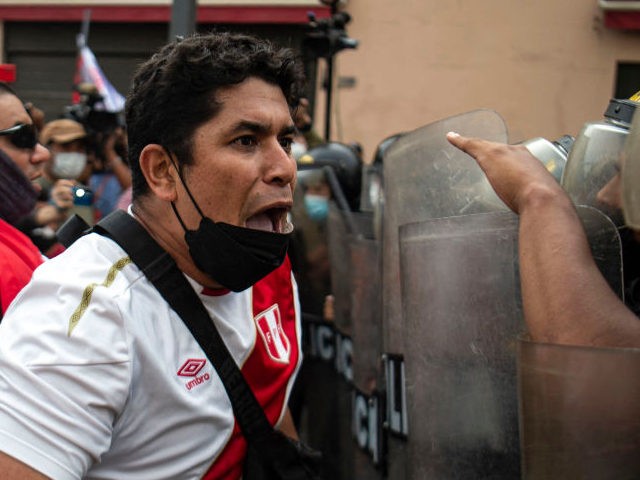 A demonstrator shouts at riot police during a protest against the governement of Peru's Pr