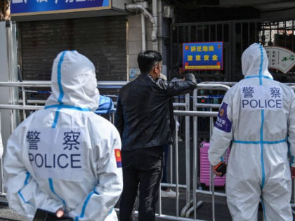 Police and officials wearing protective gear work in an area where barriers are being placed to close off streets around a locked down neighbourhood after the detection of new cases of Covid-19 in Shanghai on March 15, 2022. (Photo by Hector RETAMAL / AFP) (Photo by HECTOR RETAMAL/AFP via Getty …