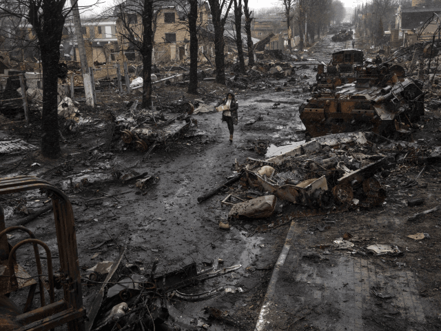 A woman walks amid destroyed Russian tanks in Bucha, in the outskirts of Kyiv, Ukraine, Su