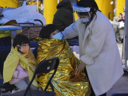 A woman with children wearing face masks wait at a temporary makeshift treatment area outside Caritas Medical Centre in Hong Kong, Friday, Feb. 18, 2022. Hong Kong's hospitals reached 90% capacity on Thursday and quarantine facilities were at their limit, authorities said, as the city struggles to snuff out a …