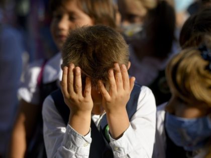 A boy wipes his eyes during festivities marking the beginning of the school year at a school in Bucharest, Romania, Monday, Sept. 13, 2021. Children returned to classrooms in Romania, a country with one of the lowest COVID-19 vaccination rates in the European Union, as the daily infection numbers continue …
