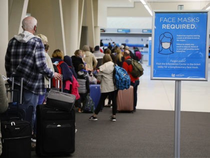 Mask requirement signs are displayed around John Glenn Columbus International Airport as travelers wait to check in Wednesday, Dec. 22, 2021, in Columbus, Ohio. For the second year in a row, the ever-morphing virus is presenting would-be revelers with a difficult choice: cancel holiday gatherings and trips or figure out …