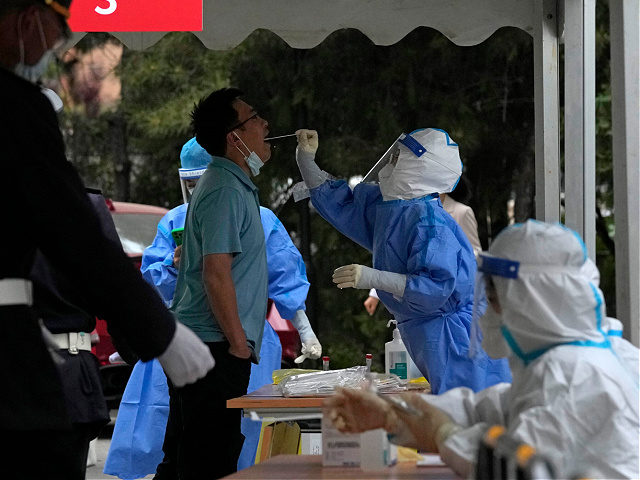 A resident gets swabbed during a mass COVID test, Wednesday, April 27, 2022, in Beijing. Workers put up fencing and police restricted who could leave a locked-down area in Beijing on Tuesday as authorities in the Chinese capital stepped up efforts to prevent a major COVID-19 outbreak like the one …