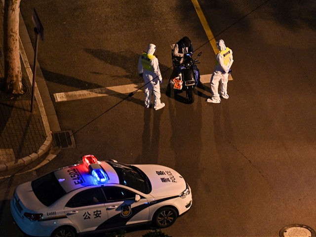 Policemen wearing personal protective equipment (PPE) check a person on a scooter on the s