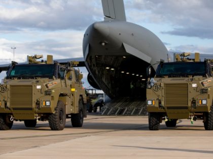 Two Bushmaster protected mobility vehicles bound for Ukraine wait to be loaded onto a C-17