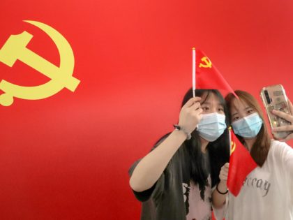 Passengers take photos with a flag of the Communist Party of China at the Nantong Railway Station in China's eastern Jiangsu province on July 1, 2021, during celebrations to mark the 100th anniversary of the founding of the Communist Party of China. - China OUT (Photo by AFP) / China …