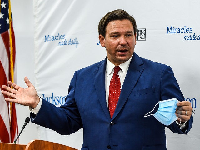 Florida Gov. Ron DeSantis speaks holding his facemask during a press conference to address