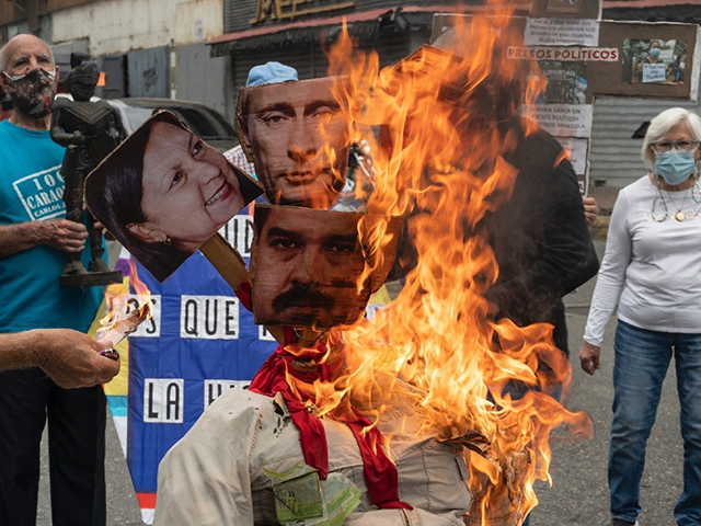 Opponents of the government of Venezuelan President Nicolas Maduro burn a dummy with the images of Maduro (C-Bottom), Russian President Vladimir Putin (C-Top) and Mayor of Caracas Carmen Melendez (L) during the traditional "burning of Judas" within the framework of the celebration of the Holy Week at La Candelaria neighborhood …