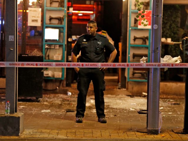 A policeman stands at the scene of a shooting attack in Dizengoff Street in the centre of Israel's Mediterranean coastal city of Tel Aviv on April 7, 2022. - At least two people were killed and several wounded during an attack in the Israeli city of Tel Aviv on April …