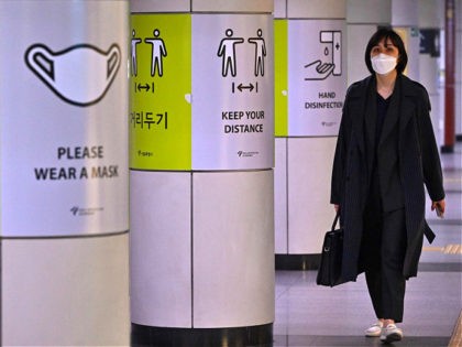 A woman walks past posters showing precautions against the Covid-19 coronavirus at a subway station in Seoul on April 15, 2022. (Photo by Jung Yeon-je / AFP) (Photo by JUNG YEON-JE/AFP via Getty Images)