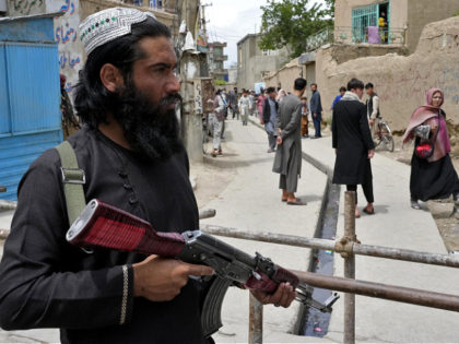 A Taliban fighter stands guard at the site of an explosion in front of a school, in Kabul,