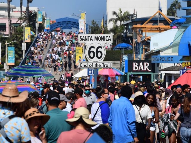 A crowd make their way to the end of the trail of Route 66 at Santa Monica Pier as people