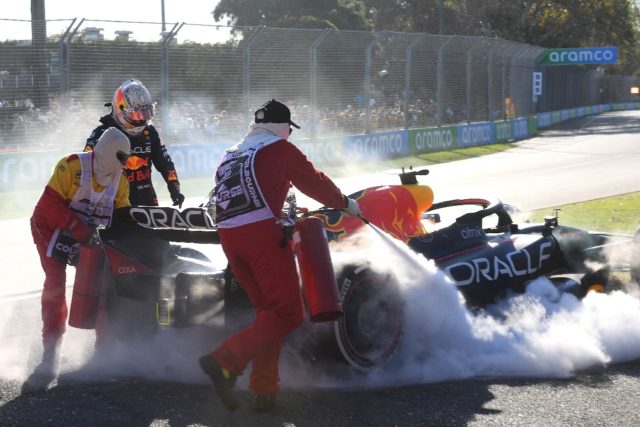 Marshals try to extinguish a fire as Red Bull's Dutch driver Max Verstappen looks on