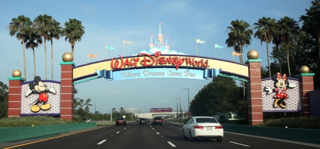 Visitors drive past a sign welcoming them to Walt Disney World in Orlando, Florida in July