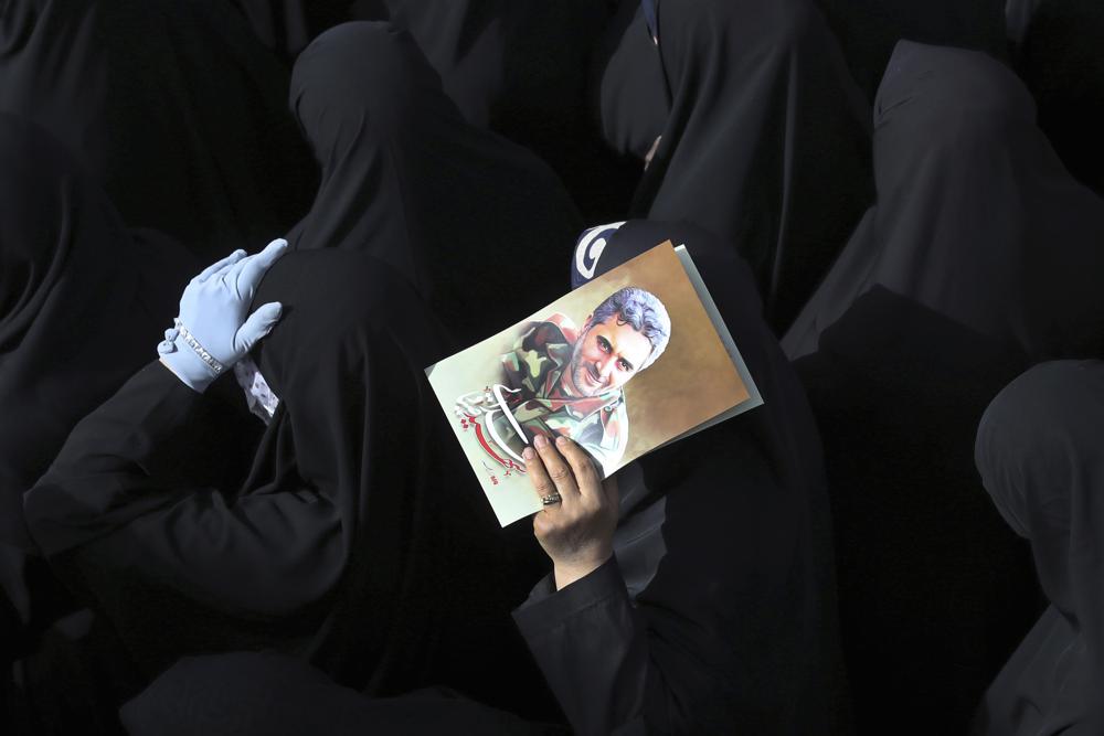 Mourners attend the funeral ceremony of Iran's Revolutionary Guard Col. Hassan Sayyad Khodaei, shown in the poster, who was killed on Sunday, in Tehran, Iran, Tuesday, May 24, 2022. Iran's hard-line President Ebrahim Raisi vowed revenge on Monday over the killing of Khodaei, who was shot at his car by two assailants outside his home in Tehran, a still-mysterious attack on the country's powerful paramilitary force. (AP Photo/Vahid Salemi)