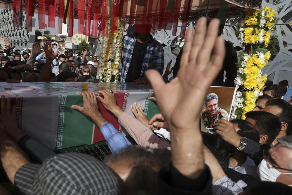 People mourn next to the flag draped coffin of Iran's Revolutionary Guard Col. Hassan Sayyad Khodaei who was killed on Sunday, in his funeral ceremony in Tehran, Iran, Tuesday, May 24, 2022. Iran's hard-line President Ebrahim Raisi vowed revenge on Monday over the killing of Sayyad Khodaei who was shot at his car by two assailants outside his home in Tehran, a still-mysterious attack on the country's powerful paramilitary force. (AP Photo/Vahid Salemi)