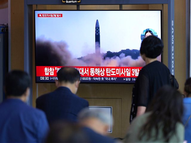 People watch a TV screen showing a news program reporting about North Korea's missile laun