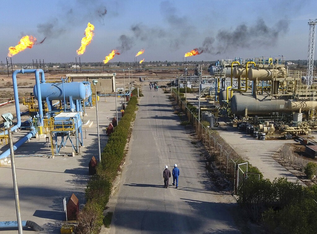 FILE - In this Jan. 12, 2017 file photo, laborers walk down a path in the Nihran Bin Omar field north of Basra, Iraq, 340 miles (550 kilometers) southeast of Baghdad. The historic crash in oil prices in the wake of the novel coronavirus pandemic is reverberating across the Middle East as crude-dependent countries scramble to offset losses from a key source of state revenue. The economies of all the Arab Gulf oil exporters are expected to contract this year. Iraq faces the most dire situation, and officials are trying to find ways to cut spending. (AP Photo/Nabil al-Jurani, File)