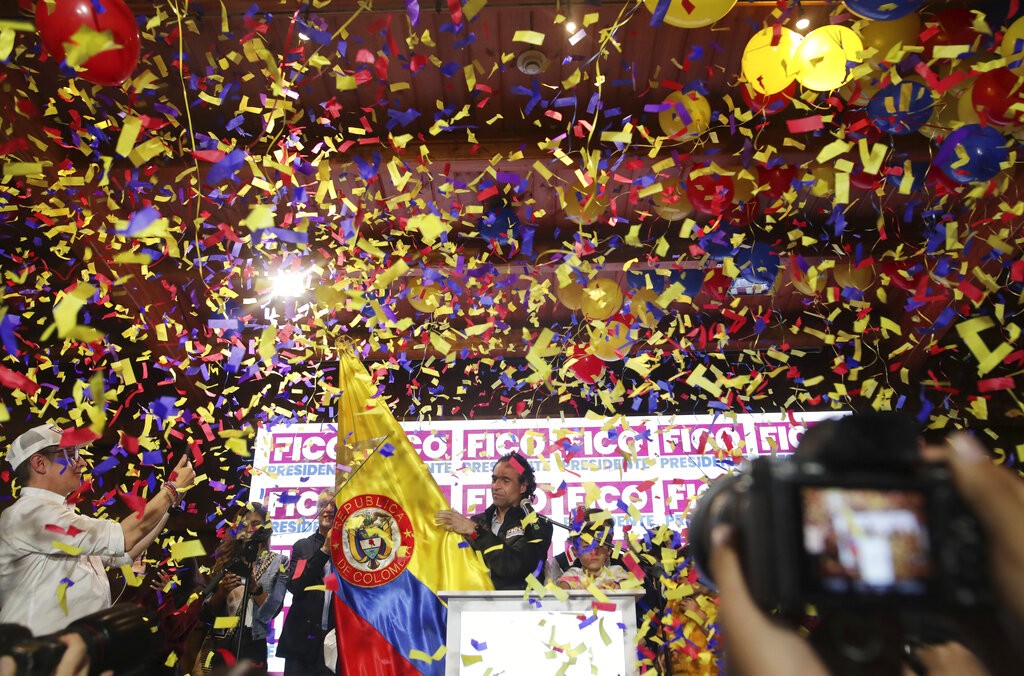 Presidential hopeful Federico Gutierrez, center, touches a Colombian flag as he celebrates after winning his coalition's primaries in legislative elections in Bogota, Colombia, Sunday, March 13, 2022. Colombians voted for a new congress on Sunday and also voted in the presidential primaries to choose the party's candidates for the presidential contest in May, as the country held its first elections since the coronavirus pandemic began two years ago.  (AP Photo/Ivan Valencia)
