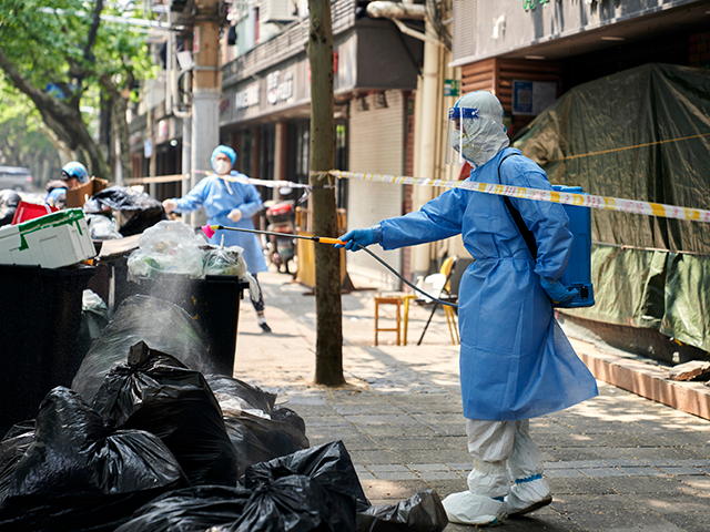 Workers in protective gear disinfect a pile of garbage bags on Thursday, April 21, 2022, i