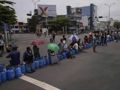 Sri Lankans demanding for cooking gas sit with their empty gas cylinders blocking a busy i