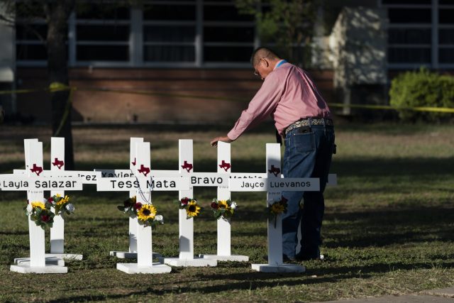 Pastor Daniel Myers places his hand on crosses bearing the names of Tuesday's shooting victims at Robb Elementary School in Uvalde, Texas, Thursday, May 26, 2022. (AP Photo/Jae C. Hong)