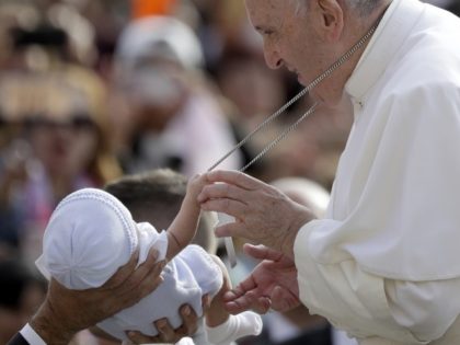 A baby handed over to Pope Francis to bless grabs onto his cross as he arrives for his wee