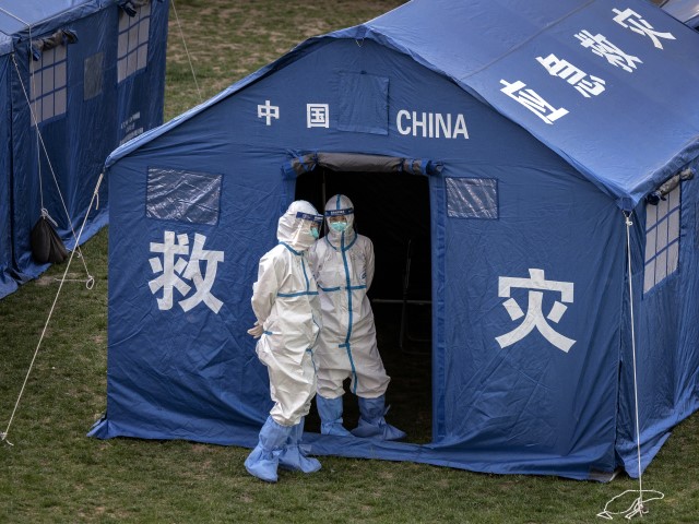 BEIJING, CHINA - APRIL 26: Health workers wear protective suits as they stand outside a tent while waiting to perform nucleic acid tests to detect COVID-19 on local workers at a makeshift testing site in Haidian District on April 26, 2022 in Beijing, China. China is trying to contain a spike in coronavirus cases in the capital Beijing after dozens of people tested positive for the virus in recent days, causing local authorities to initiate mass testing in most districts and to lockdown some neighbourhoods where cases are found in an effort to maintain the country's zero COVID strategy.