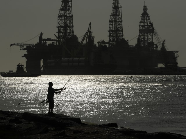 FILE - A man wears a face mark as he fishes near docked oil drilling platforms, on May 8, 2020, in Port Aransas, Texas. A federal court has rejected a proposed lease auction for offshore oil drilling in the Gulf of Mexico, saying the Biden administration failed to conduct a proper environmental review. The decision on Jan. 27, 2022, by U.S. District Judge Rudolph Contreras sends the proposed lease sale back to the Interior Department to decide next steps. (Eric Gay, File/AP)