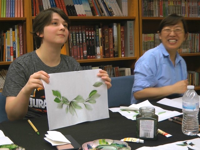 Undergraduate student Moe Lewis, left, shows her watercolor painting of peony leaves at a traditional Chinese painting class at the Confucius Institute at George Mason University in Fairfax, Virginia, on May 2, 2018. U.S. lawmakers are pushing for tighter regulation or even closure of the more than a hundred Chinese Confucius Institutes set up on campuses across America. (Matthew Pennington/AP)