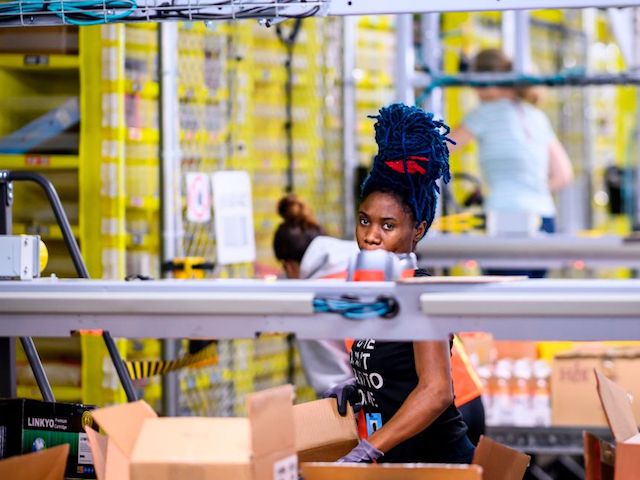 A woman works at a distrubiton station at the 855,000-square-foot Amazon fulfillment center in Staten Island, one of the five boroughs of New York City, on February 5, 2019. - Inside a huge warehouse on Staten Island thousands of robots are busy distributing thousands of items sold by the giant of online sales, Amazon. (Photo by Johannes EISELE / AFP) (Photo credit should read JOHANNES EISELE/AFP via Getty Images)