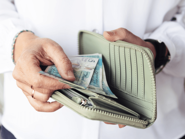 Woman taking out pounds from her pocket wallet - stock photo