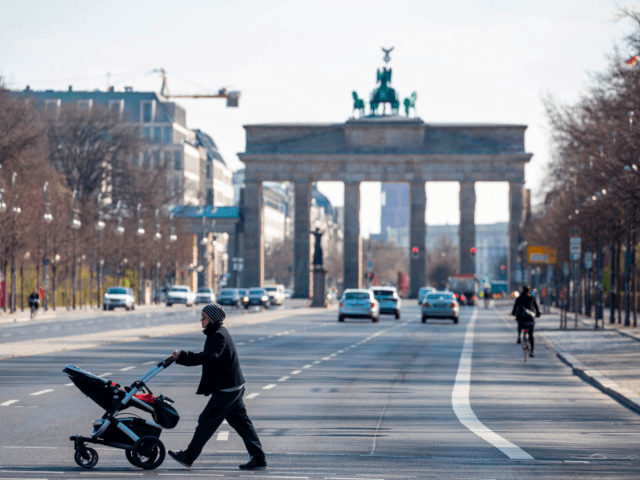 A woman pushing a pram crosses an almost deserted 17th June street near Brandenburger gate in Berlin on April 1, 2020 as Germany continues its battle against the Covid-19 corona virus. - The avenue leading up to the landmark Brandenburger Gate is normally one of the busiest stretches of road …