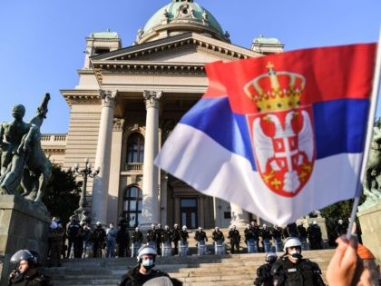 Police stand on the front steps of the Serbia's National Assembly building as protesters gather in Belgrade on July 8, 2020 against a weekend curfew announced to combat a resurgence of COVID-19 infections despite Serbia's president said today it might be scrapped after the measure sparked the day before angry …
