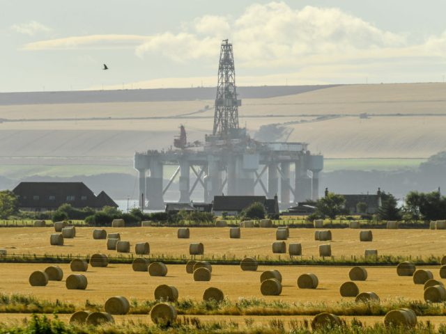 INVERGORDON, SCOTLAND - SEPTEMBER 08: An oil rig is seen towering over a field of hay bale