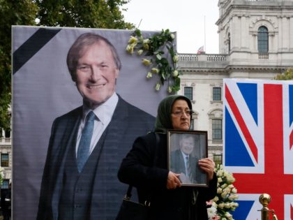 A member of the Anglo-Iranian community and supporters of the National Council of Resistance of Iran (NCRI) holds a photograph during a memorial service to pay tribute to slain British lawmaker David Amess in Parliament Square in front of the Houses of Parliament in central London on October 18, 2021. …