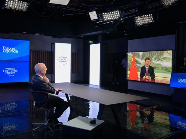 TOPSHOT - Founder and Executive Chairman of the World Economic Forum (WEF) Klaus Schwab listen Chinese President Xi Jinping seen on the TV screen speaking remotely at the opening of the WEF Davos Agenda virtual sessions at the WEF's headquaters in Cologny near Geneva on January 17, 2022. (Photo by …
