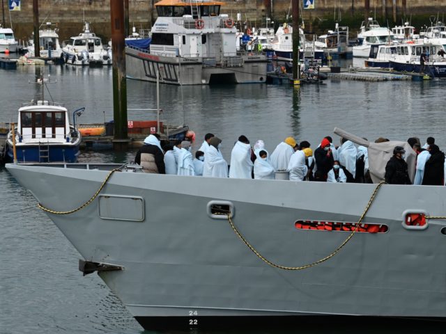 Migrants huddle together under blankets, brought to port by the UK Border Force after bein
